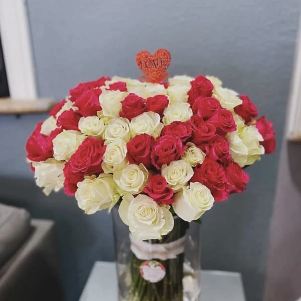 Bouquet of red and white roses in a clear vase with a heart topper