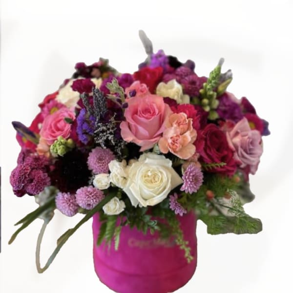 Bouquet of pink, white, and purple flowers in a bright pink container