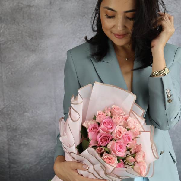 Woman holding a bouquet of pink roses wrapped in pale paper