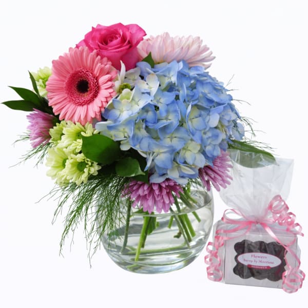 Mixed bouquet in a glass vase with pink, blue, and green flowers