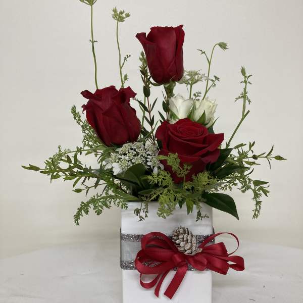 Red and white roses arranged in a white gift box with a red ribbon