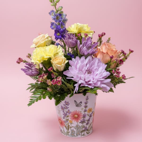 Mixed pastel flowers arranged in a decorative floral pot