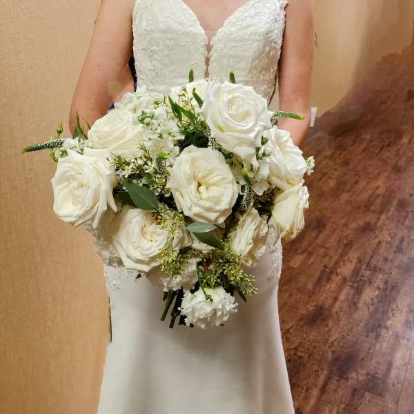 Bride holding a bouquet of white roses and greenery