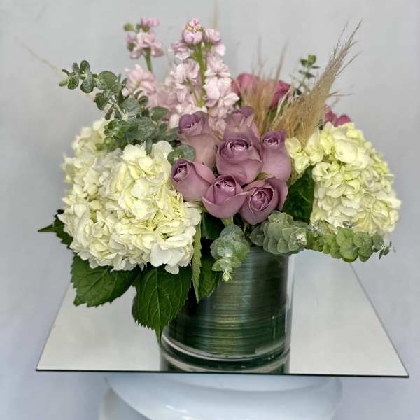 Lavender roses and pale hydrangeas in a green glass vase