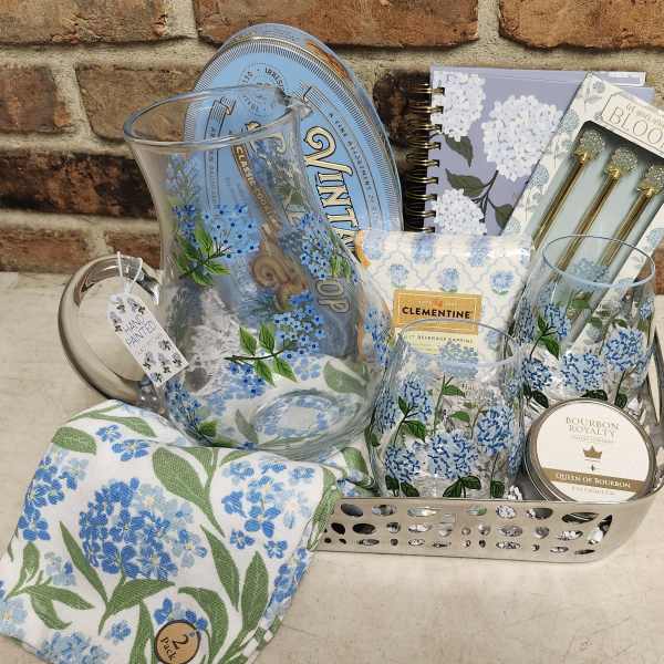 Gift basket with floral-print glassware, notebook, candle, and napkins