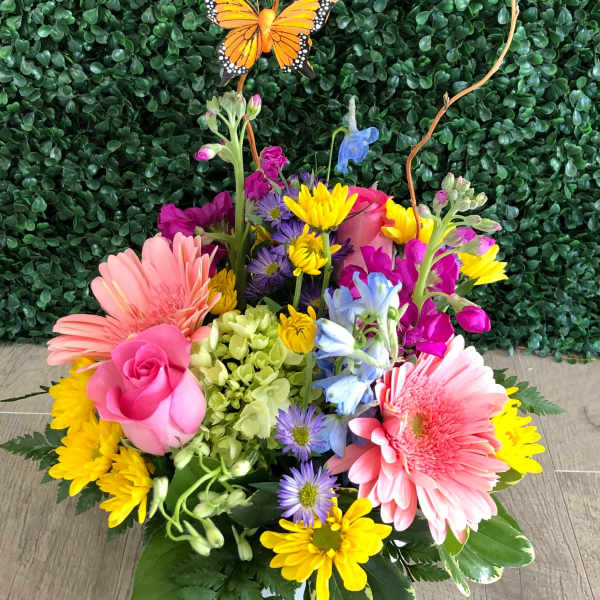 Colorful mixed bouquet in a white vase with a butterfly pick