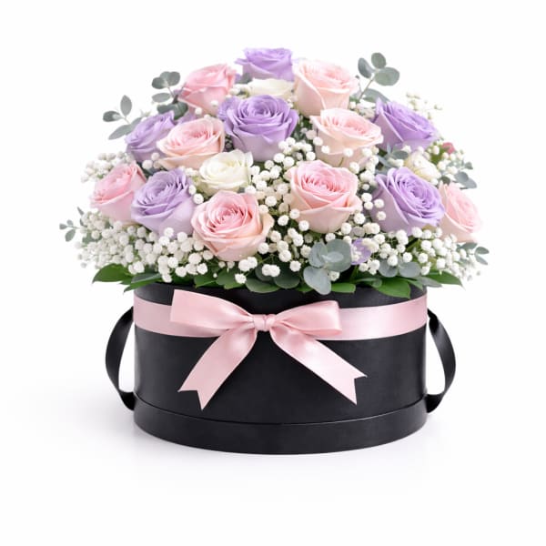 Pink and lavender roses in a black hat box with a pink ribbon
