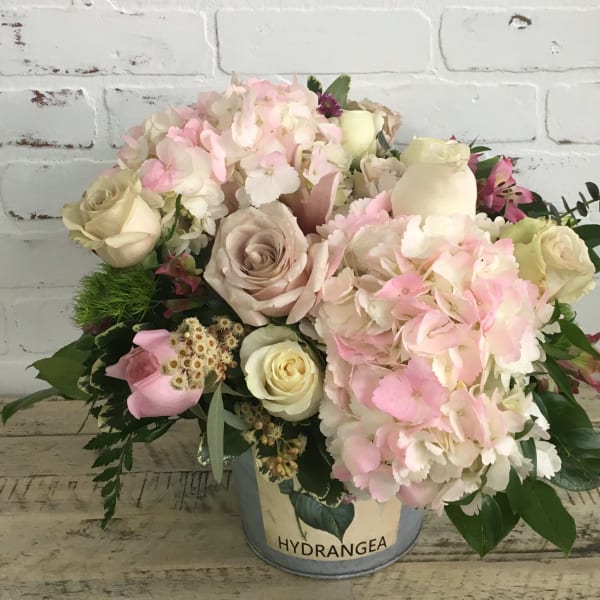 Pink and cream bouquet in a metal bucket with hydrangeas and roses