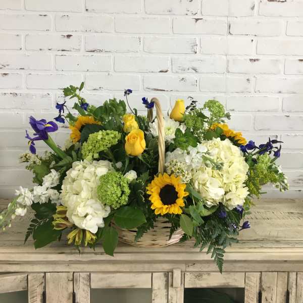 Basket of yellow, white, and blue flowers on a rustic table