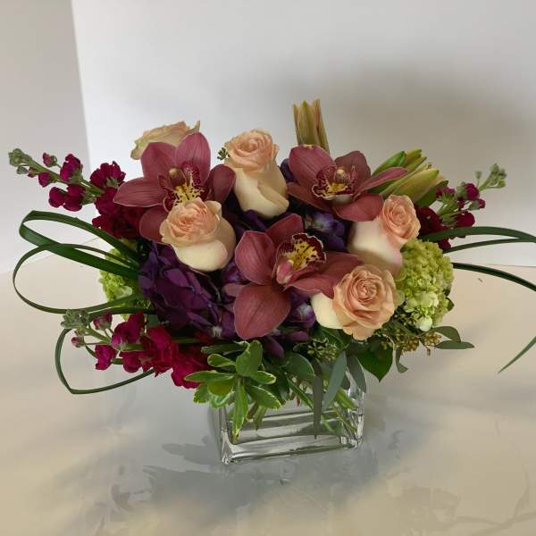 Bouquet of pink orchids and peach roses in a clear glass vase