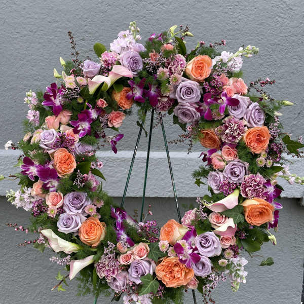 Circular floral wreath with roses, calla lilies, and orchids on a stand