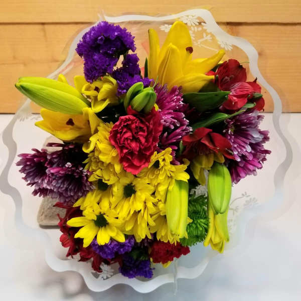 Bouquet of yellow lilies, purple chrysanthemums, and red alstroemeria in clear wrap