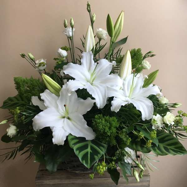White lilies and small white blooms in a basket arrangement