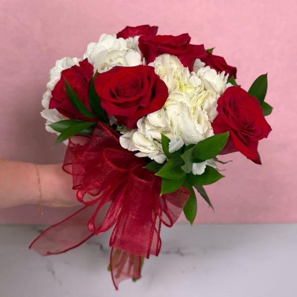 Bouquet of red roses and white hydrangeas tied with a red ribbon