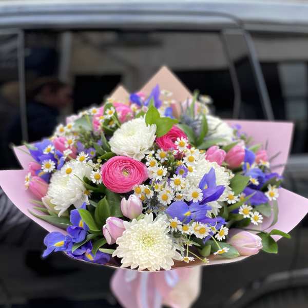 Bouquet of pink, white, and blue flowers wrapped in pink paper