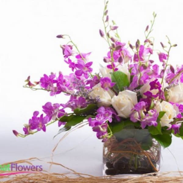 Purple orchid bouquet with white roses in a glass vase