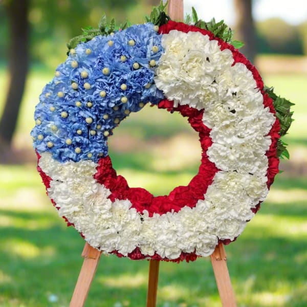 Circular floral wreath in red, white, and blue on a wooden easel