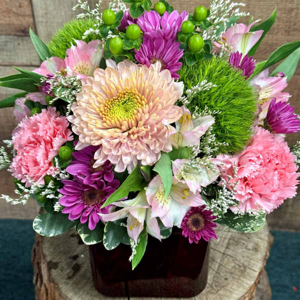 Pink and purple mixed flower arrangement in a dark vase