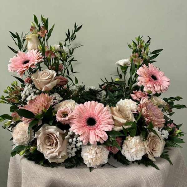 Pink gerbera daisies and cream roses arranged in a low floral display
