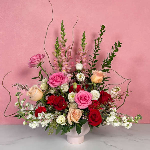 Mixed roses and pink snapdragons in a pale vase