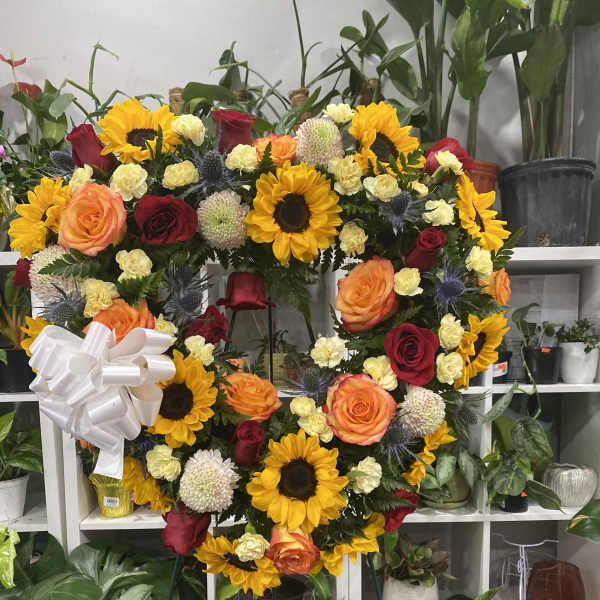 Heart-shaped floral wreath with sunflowers, roses, and a white bow