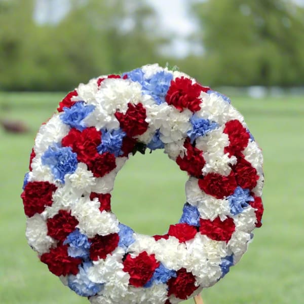 Circular wreath of red, white, and blue carnations on a stand