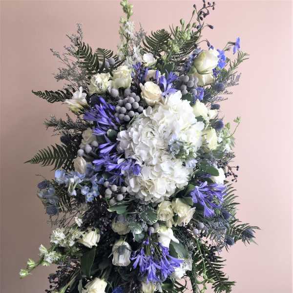 Tall white and blue floral standing spray with roses and hydrangea