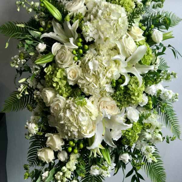 Large white and green floral standing spray with roses, lilies, and hydrangeas