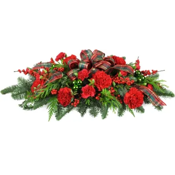 Red carnations and berries arranged with plaid ribbon on evergreen