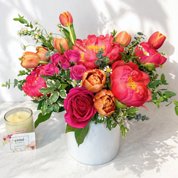Bright mixed bouquet of pink and orange flowers in a white vase
