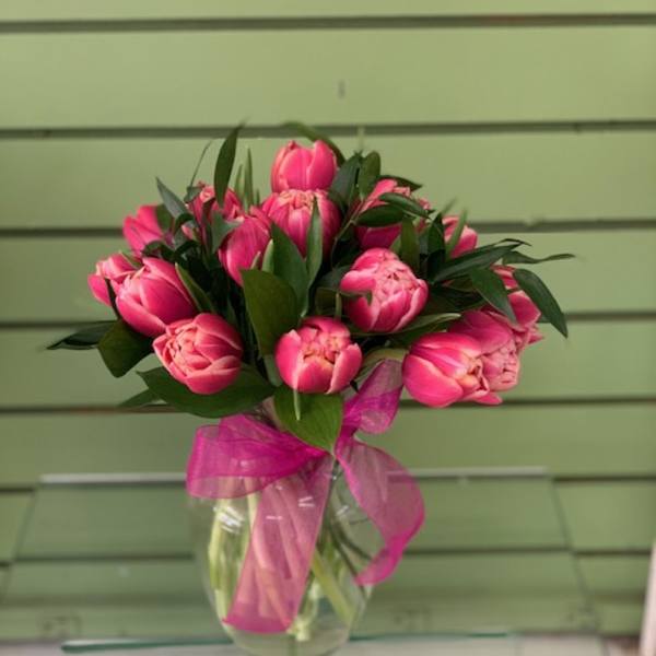 Pink tulip bouquet in a clear glass vase with a pink ribbon