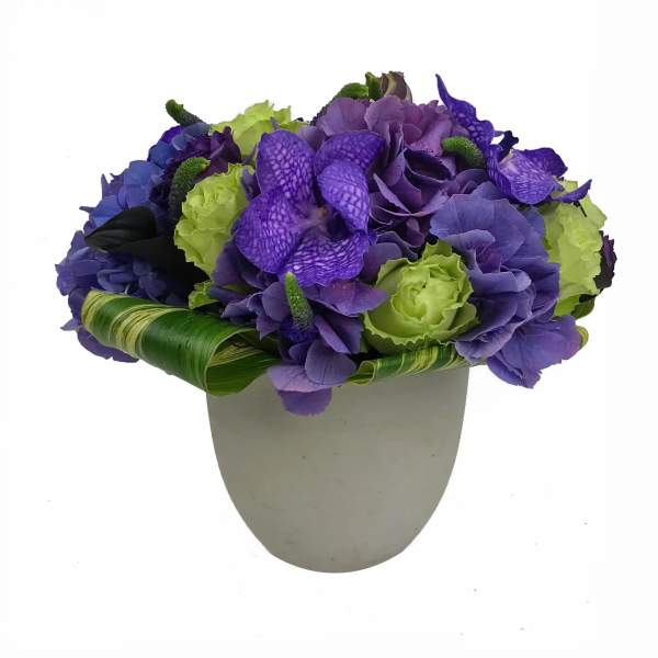 Purple and green floral arrangement in a white vase