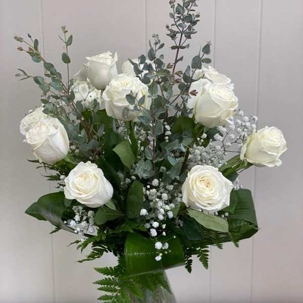 White roses and baby's breath in a clear glass vase