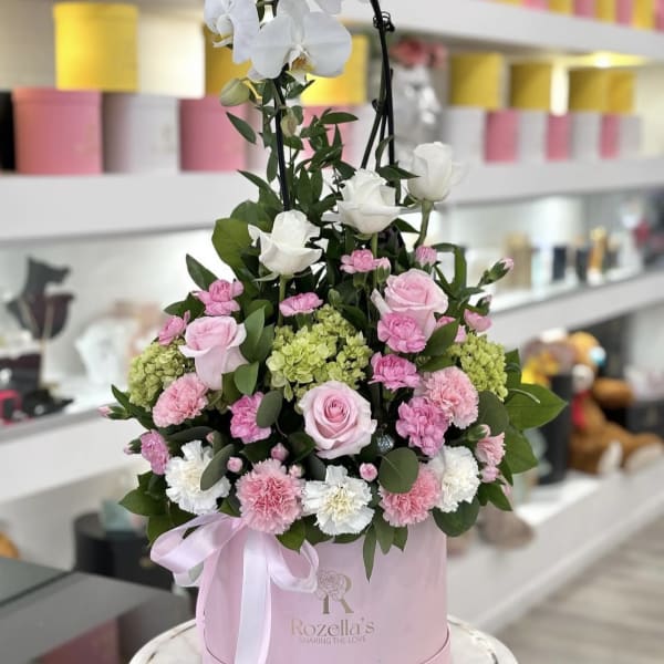 Pink and white floral arrangement in a round pink box