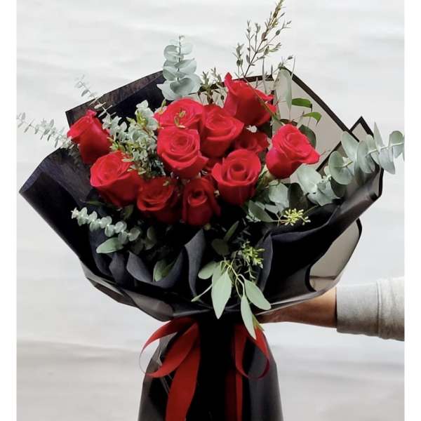 Bouquet of red roses wrapped in black paper with a red ribbon