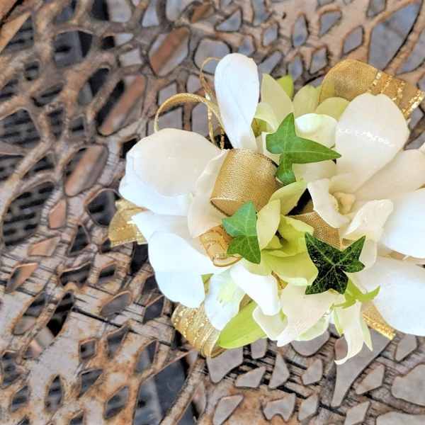White floral corsage with gold ribbon and ivy accents