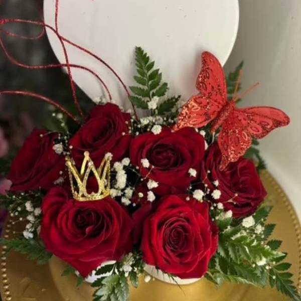 Red roses arranged with a gold crown and red butterfly in a heart-shaped box