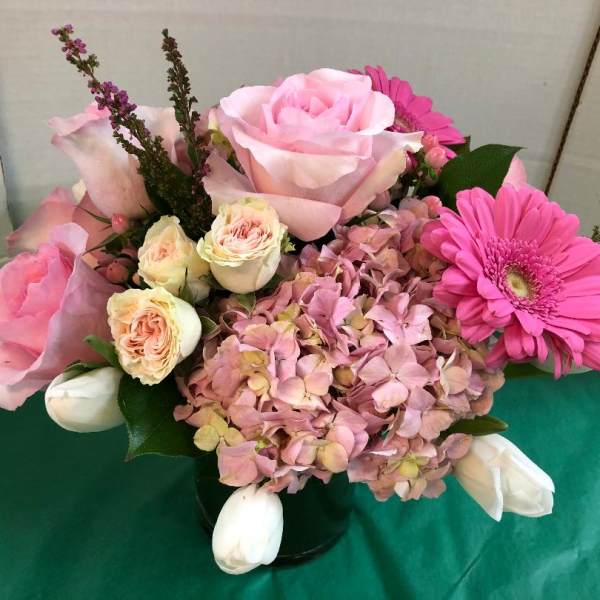 Pink roses and hydrangea in a black vase with a pink gerbera daisy