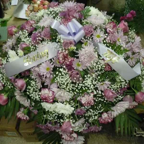 Large pink and white floral wreath with ribbon banners