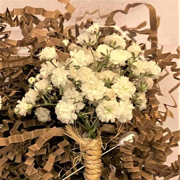 Small bouquet of white flowers wrapped in brown paper