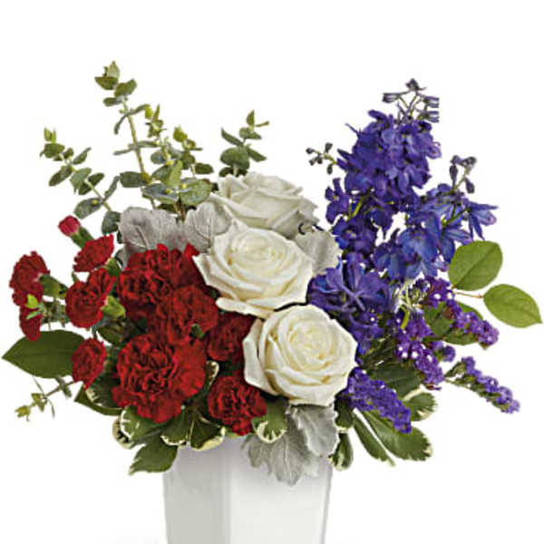 Red and white roses with purple flowers in a white vase