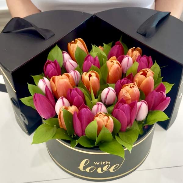 Bouquet of pink, orange, and white tulips in a black round box