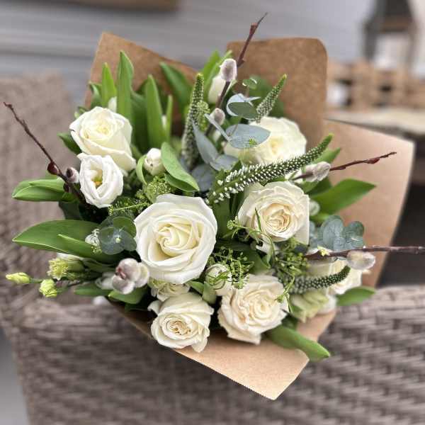 Bouquet of white roses with greenery and brown paper wrap