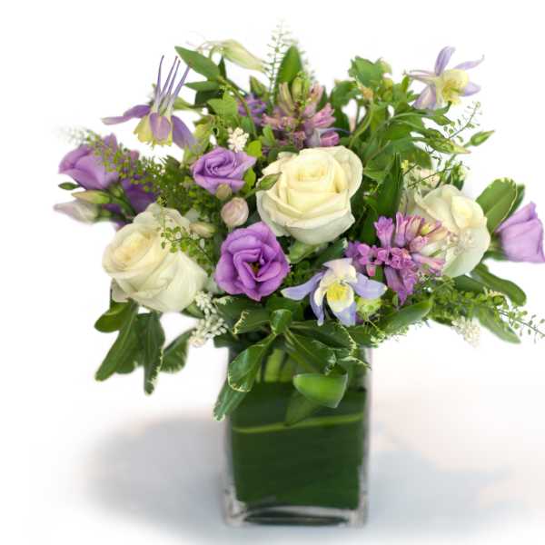Purple and white mixed bouquet in a square glass vase
