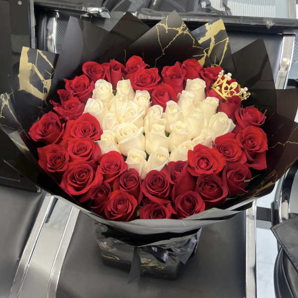 Bouquet of red and white roses wrapped in black paper with gold accents