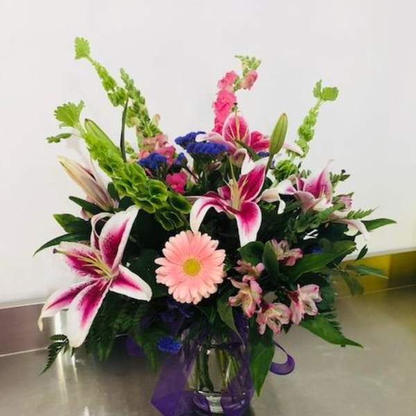 Mixed bouquet in a glass vase with pink lilies and a pink daisy