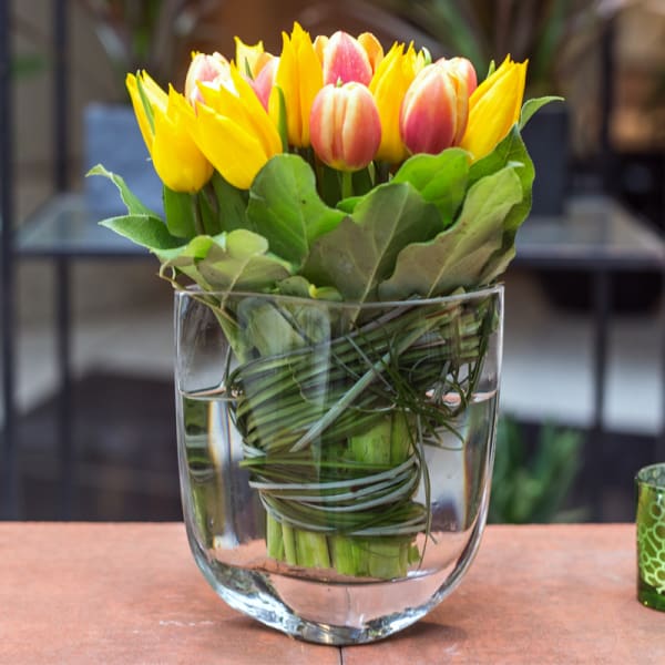 Yellow and pink tulips arranged in a clear glass vase