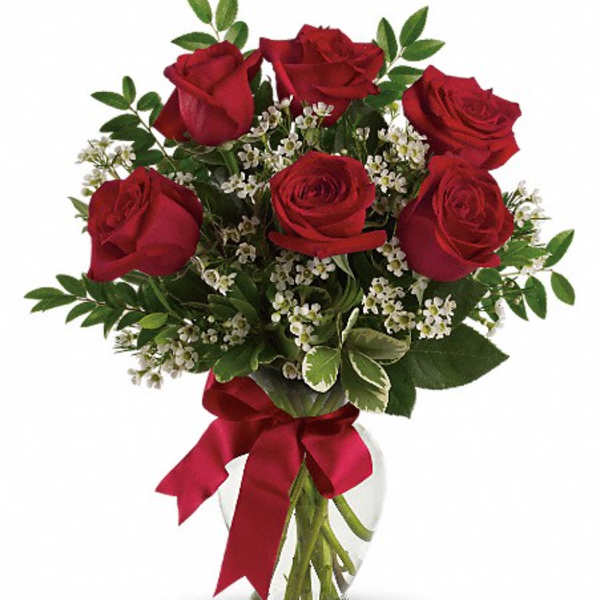 Red roses in a clear glass vase with a red ribbon
