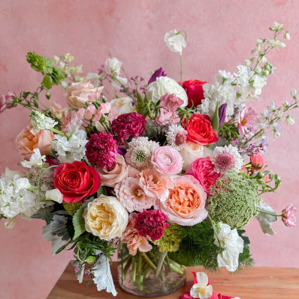 Mixed bouquet of pink, white, and coral flowers in a glass vase