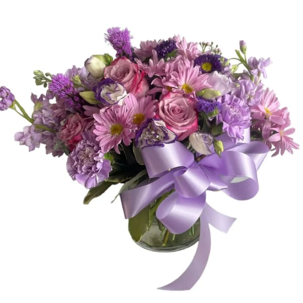 Lavender and pink bouquet in a glass vase with a purple ribbon